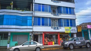 A hostel building with a sign reading "HOSTAL" and a storefront below. - Hostal Amazónico Bello Amanecer (Nueva Loja)