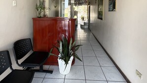 A hallway with a reception desk, chairs, and a potted plant. - Hostal Amazónico Bello Amanecer (Nueva Loja)