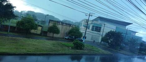 Una zona residencial con un edificio de dos pisos, un espacio con césped y automóviles estacionados.