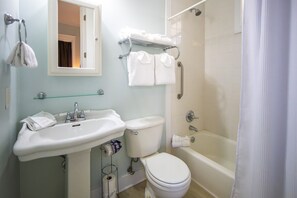 Un bagno con lavandino, WC e vasca da bagno. Asciugamani su un porta asciugamani e uno specchio sopra il lavandino.