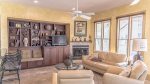 A living room with a fireplace, sofa, TV, and decorative shelves. - LOCATION! 100ft from PRIVATE beach access (Santa Rosa Beach)