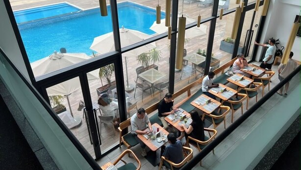 A restaurant with outdoor seating overlooking a swimming pool. - Embassy Gardens - One Bed (Accra)