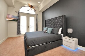 A bedroom with a bed, a nightstand, a ceiling fan, and a TV mounted on the wall. - Love&Mystique Getaway in Galleria w/ Pool //Sleeps12! (Houston)