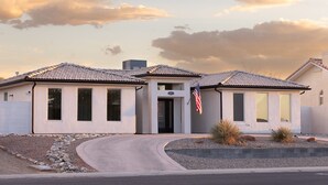 A single-story house with a tiled roof, a front entrance, and an American flag. - Desert Ranch House (Page)