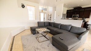 A modern living room with a grey sectional sofa, a glass coffee table, and a patterned rug. - Desert Ranch House (Page)