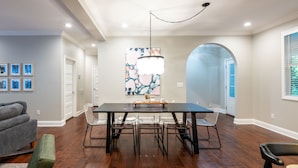 Un comedor con una mesa rectangular, seis sillas y una araña.