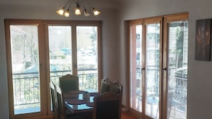 A spacious dining area with a wooden table and chairs, a chandelier, and large windows with blinds.