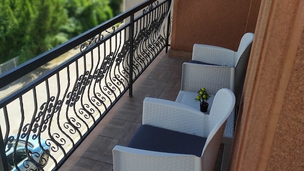 A balcony with two white wicker chairs, a small table, and a potted plant.