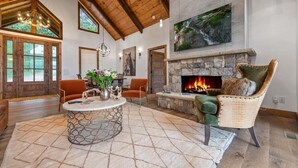 Un salón amplio con chimenea de piedra, vigas de madera en el techo y un ventanal grande.