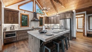 Una cocina amplia con una isla grande, vigas de techo de madera y electrodomésticos modernos.