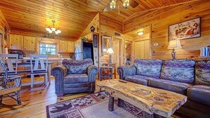 A cozy cabin interior with a wooden ceiling, a dining area with a table and chairs, and a seating area with a sofa and armchairs. - Amy's Blue Ridge Mtn & Starlight View (Ellijay)