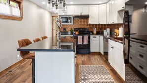 A modern kitchen with white cabinets, a central island, and a patterned backsplash. - Stylish Uptown Butte Condo - 632 (Butte)