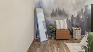 A room with a large mirror, a brown leather sofa, a white pillow, a potted plant, and a woven basket. - Stylish Uptown Butte Condo - 632 (Butte)