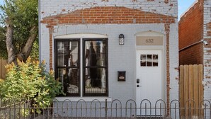 A small, single-story building with a white brick facade, a white door, and a large window. - Stylish Uptown Butte Condo - 632 (Butte)