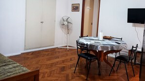 A room with a wooden herringbone floor, a ceiling fan, a dining table with chairs, a TV, and a wardrobe. - 2 ambientes zona facultad de medicina (Buenos Aires)