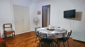 A dining area with a round table, chairs, a fan, a television, and a wardrobe. - 2 ambientes zona facultad de medicina (Buenos Aires)