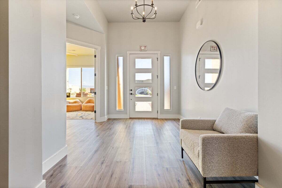 A spacious hallway with a wooden floor, a beige sofa, and a large mirror on the wall.