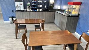 A restaurant interior with wooden tables and chairs, a counter with a coffee machine, and a popcorn machine. - Champion Inn (Shepherd)