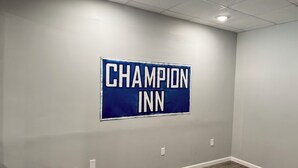 A room with a sign reading "CHAMPION INN" on the wall, a wooden floor, and a ceiling with recessed lighting. - Champion Inn (Shepherd)