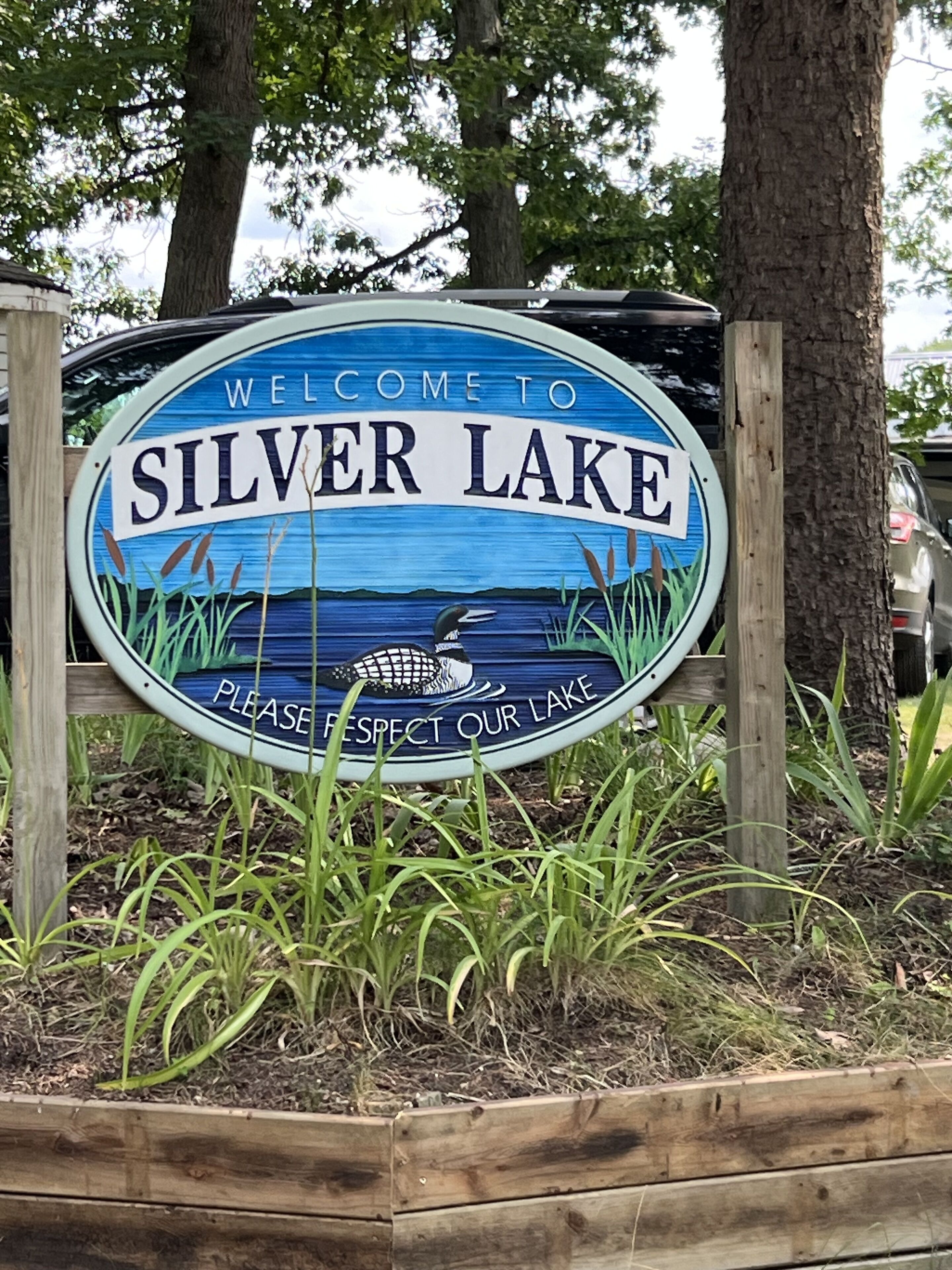 Letrero de bienvenida a Silver Lake con una ilustración de un pato y un mensaje para respetar el lago.