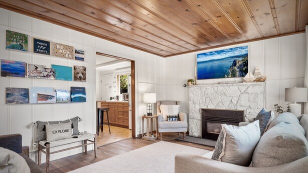 A cozy living room with a fireplace, a comfortable sofa, and a dining area with wooden cabinets. - Steps From the Beach. Tahoe Tipsy Trout. It's a VIBE (Kings Beach)