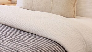 A neatly made bed with white linens and a striped blanket, a bedside lamp, and a white headboard. - Steps From the Beach. Tahoe Tipsy Trout. It's a VIBE (Kings Beach)