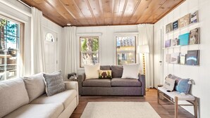 A cozy living room with a wooden ceiling, a grey sofa, a white sofa, a wooden bench, and a rug. - Steps From the Beach. Tahoe Tipsy Trout. It's a VIBE (Kings Beach)