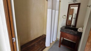 Un bagno con una panca in legno, un lavandino con specchio e tende bianche.