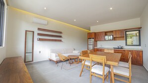 Una cucina moderna con mobili in legno, un'area pranzo con tavolo e sedie in legno e un divano bianco.