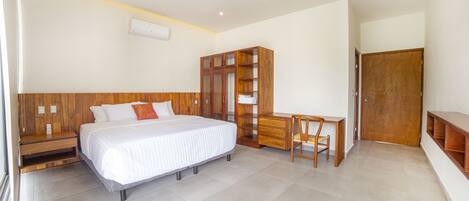 A bedroom with a bed, a wooden wardrobe, a desk, and a chair.