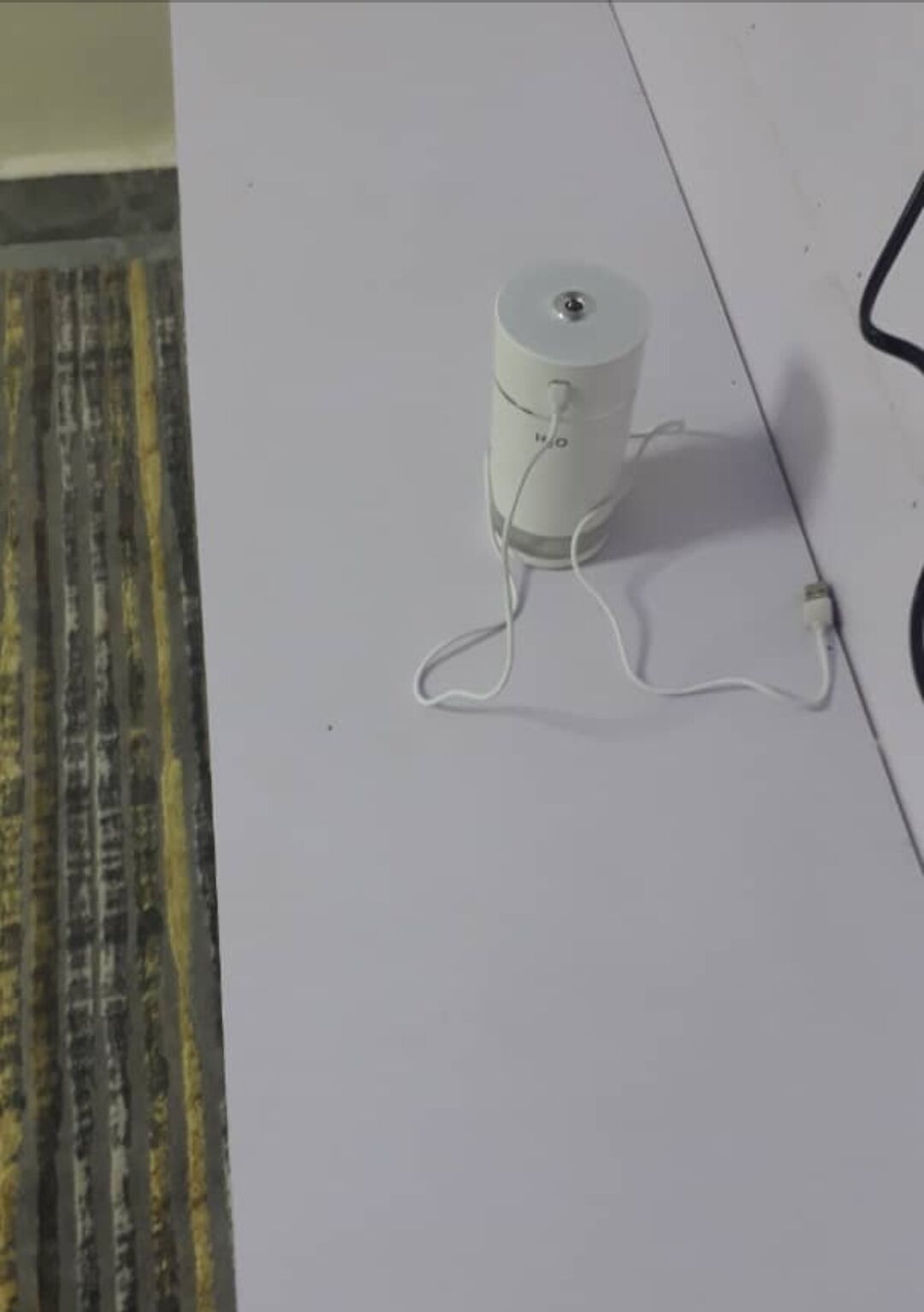 A white cylindrical device with a cord, labeled "W/O," on a white surface.
