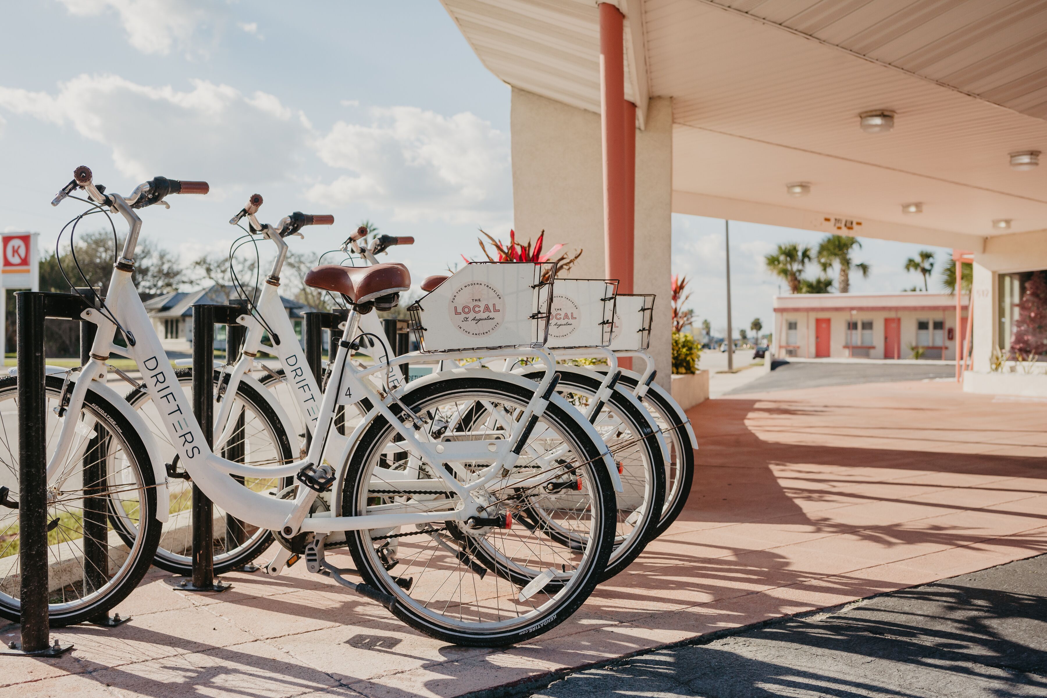 A row of white bicycles parked at a gas station with a canopy overhead.