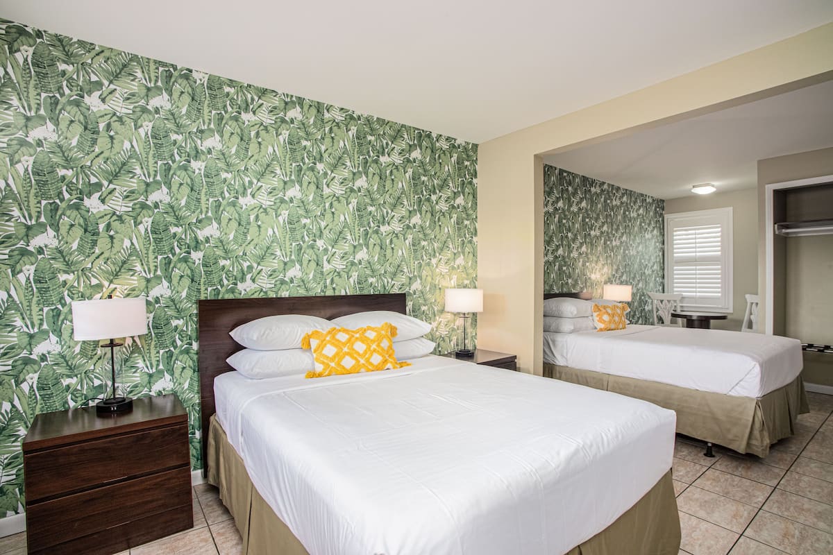 Une chambre d’hôtel avec deux lits, une table de chevet en bois et un miroir.