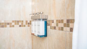 A bathroom with a wall-mounted soap dispenser and a tiled backsplash.