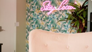 A room with a tufted headboard, a neon sign reading "Stay Local," and a wall with a tropical leaf pattern. - The Local - St. Augustine (St. Augustine)