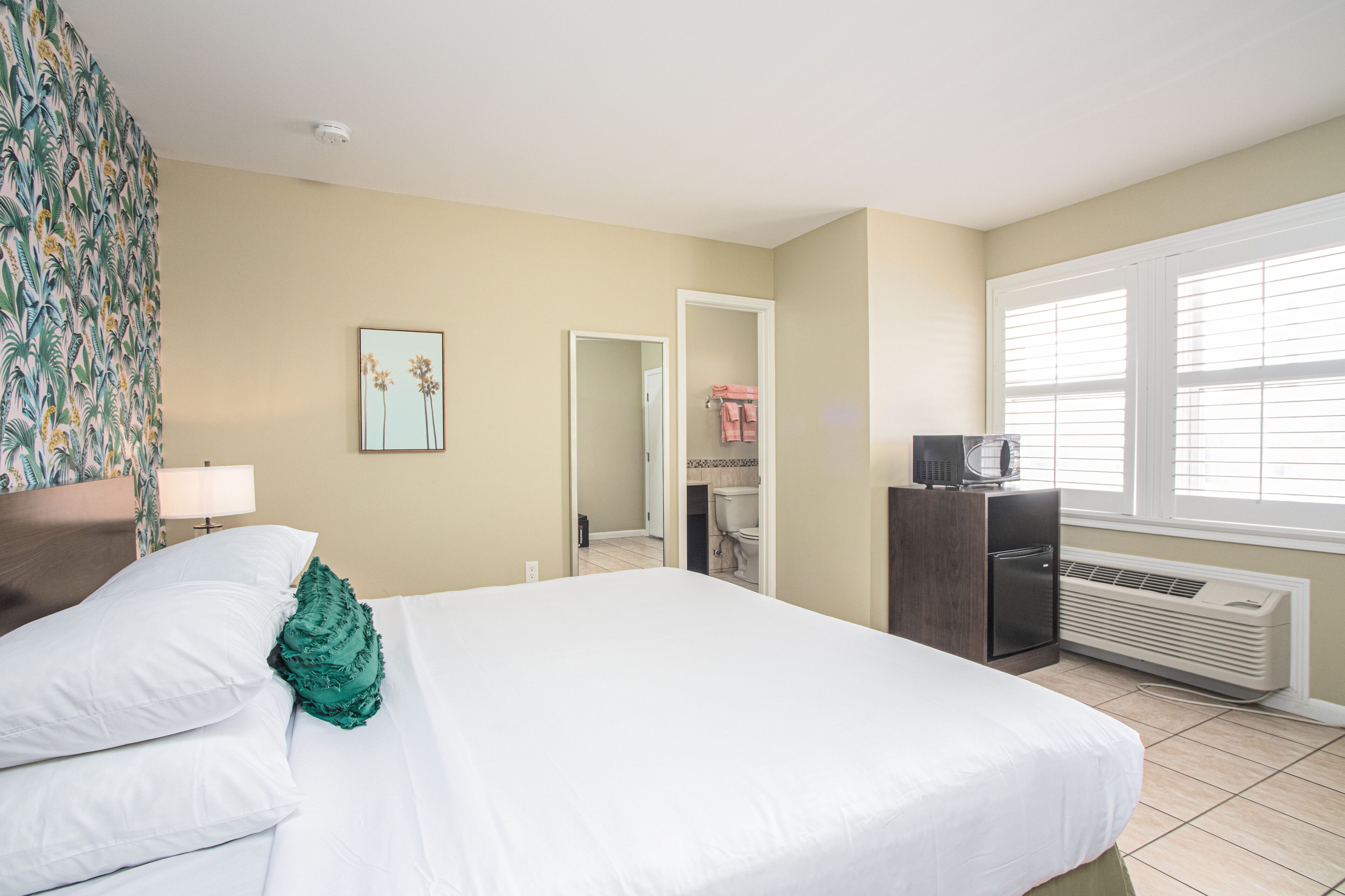 A hotel room with a bed, a desk, a heater, and a window.