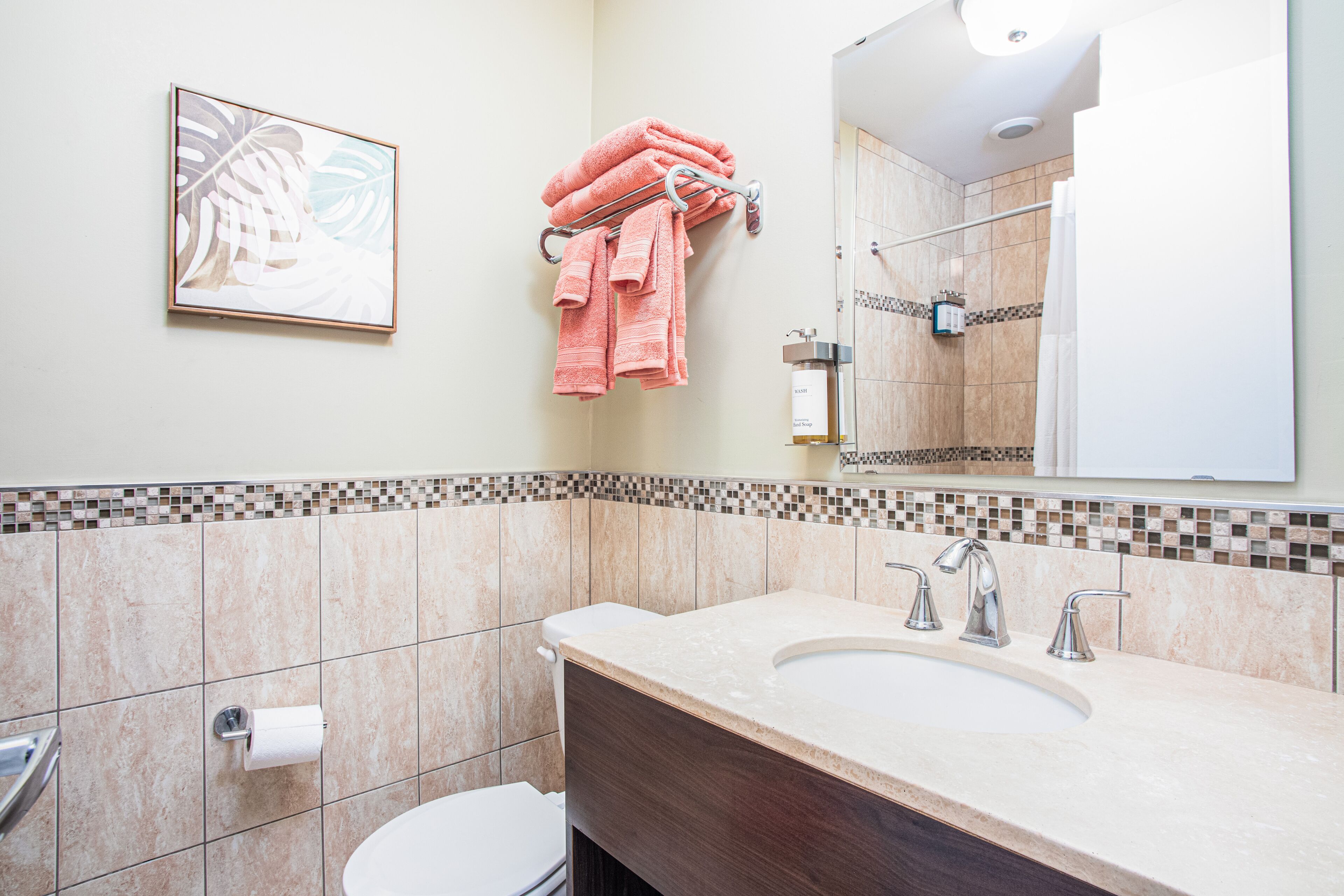 Une salle de bain avec un lavabo beige, deux robinets, des toilettes et un miroir.