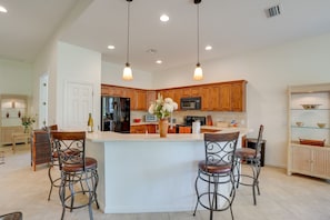 Una cocina amplia con una isla central, armarios de madera e iluminación colgante.