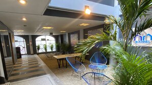 Een lobby met een trap, een eetgedeelte met tafels en stoelen, en een bordje met de tekst 'Mexico City Roomies'.