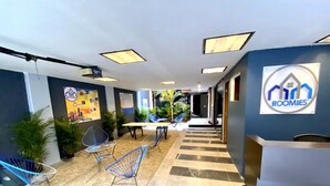 Een moderne lounge met een receptiebalie, zitplaatsen en uitzicht op een kamer.