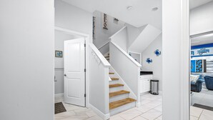 A modern interior with a staircase leading to a kitchen area. - Beachside Escape Magnolia Townhome w/Game Room, Fire pit, BBQ grills & Private Balcony! (Cape Canaveral)