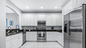 A modern kitchen with white cabinets, stainless steel appliances, and a tiled floor. - Beachside Escape Magnolia Townhome w/Game Room, Fire pit, BBQ grills & Private Balcony! (Cape Canaveral)