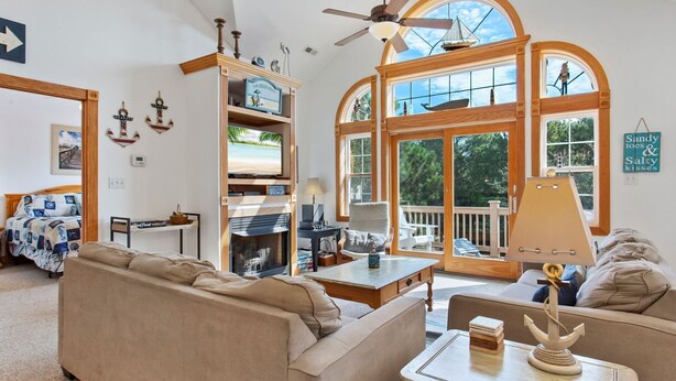 A spacious living room with a large window, a fireplace, and a cozy seating area. - Castaway: Private Pool, Hot Tub & Ocean Breeze (Corolla)