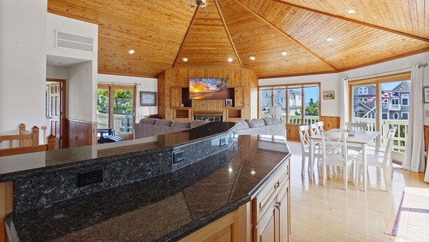 A spacious kitchen with a granite countertop, wooden ceiling, and a large island. - Nautica Nook: Ocean Escape with Saltwater Pool (Corolla)