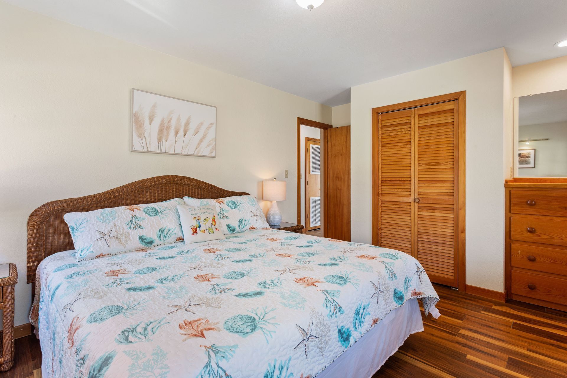 A bedroom with a bed, a nightstand, a wooden wardrobe, and a framed picture on the wall.