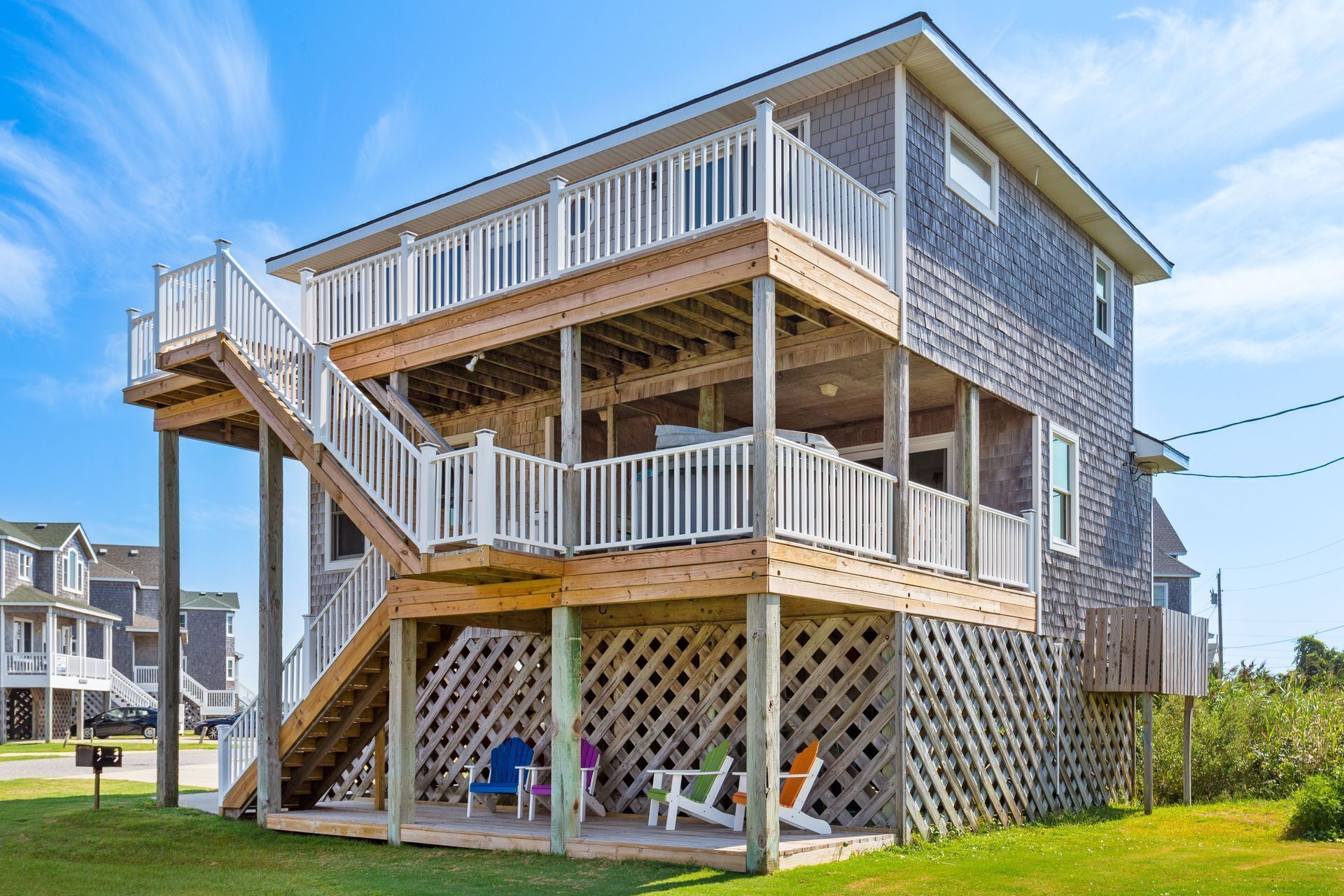A multi-level wooden house with a balcony and a covered outdoor seating area.