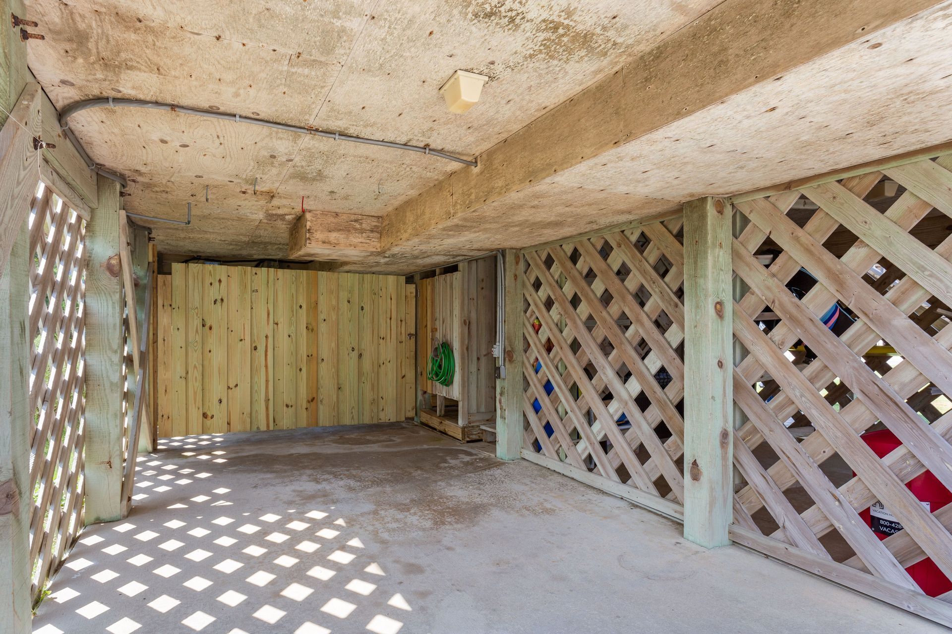A room with a concrete floor, wooden walls, and a lattice partition.