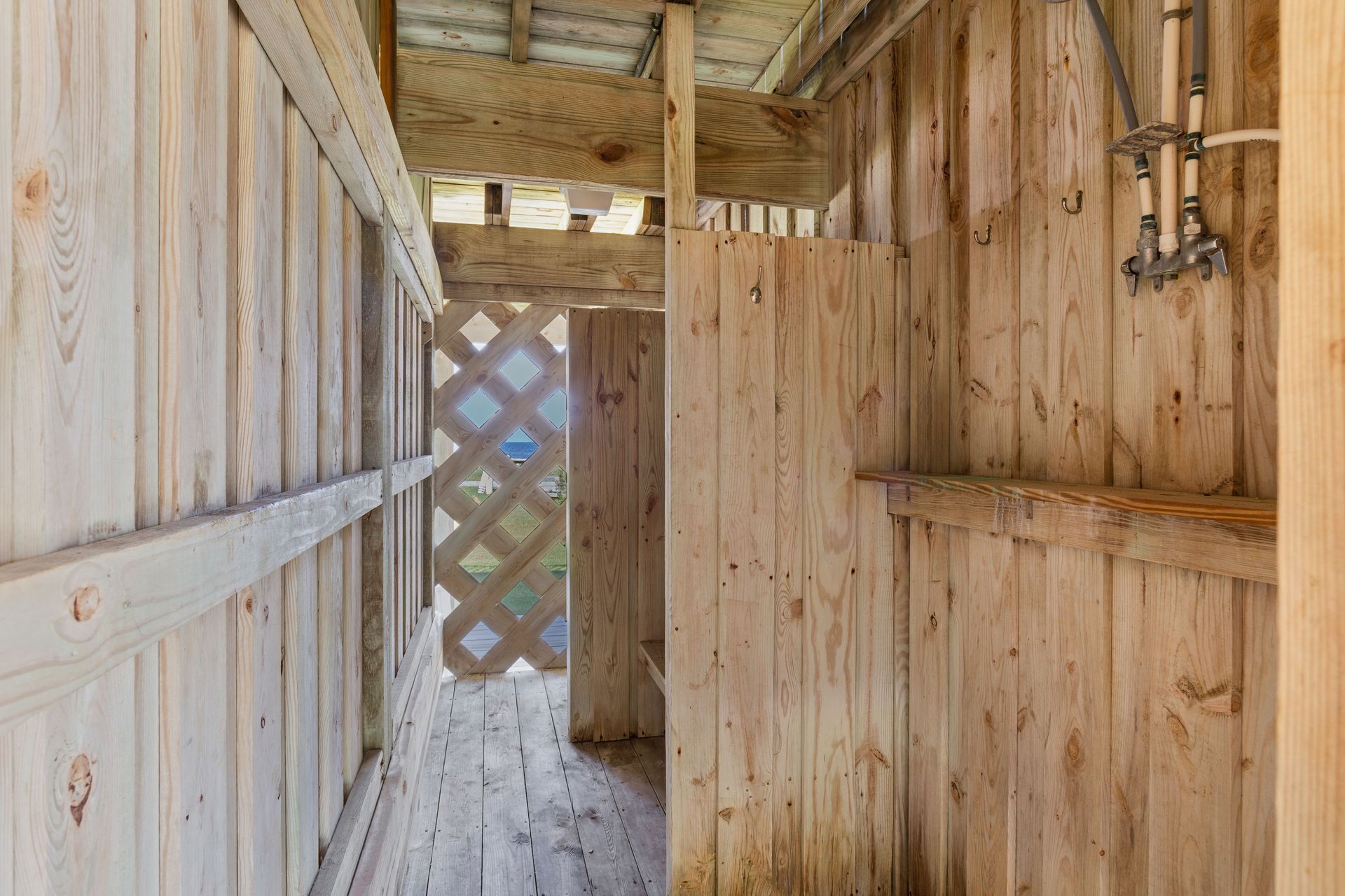 Un interior de madera con una ventana celosíaca, vigas de madera y un tubo de metal en la pared.