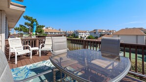 A deck with outdoor furniture, including chairs and a table, overlooking a residential area with houses. - Pet-Friendly Sea Dunes Townhome Near Beach (Kitty Hawk)