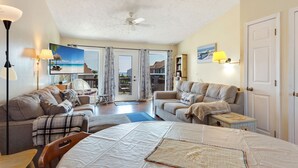 A spacious living room with a large bed, two sofas, a coffee table, and a ceiling fan. - Pet-Friendly Sea Dunes Townhome Near Beach (Kitty Hawk)